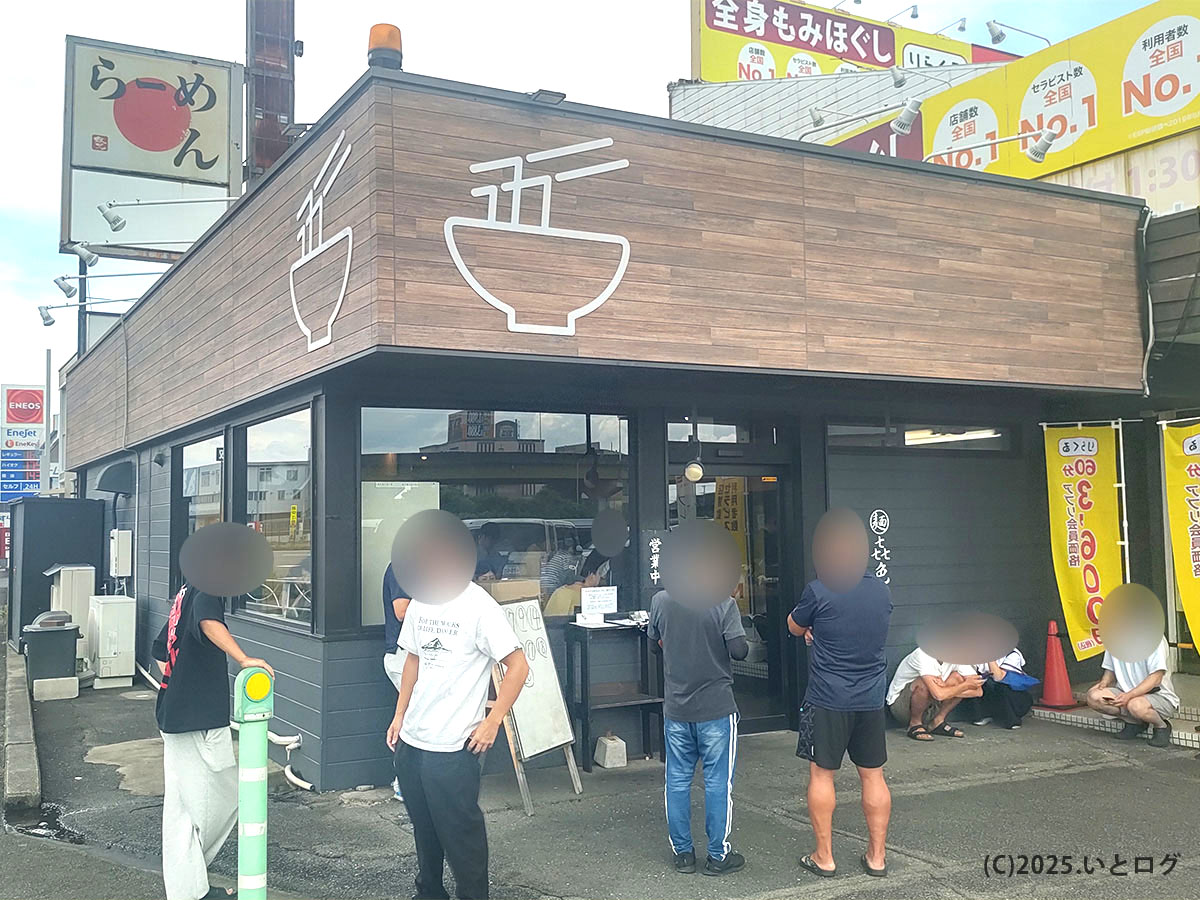 麺 㐂色の店舗外観。駐車場には車が停まり、店頭には行列ができる人気ぶり。おすすめラーメンを求めて多くの人が訪れる。