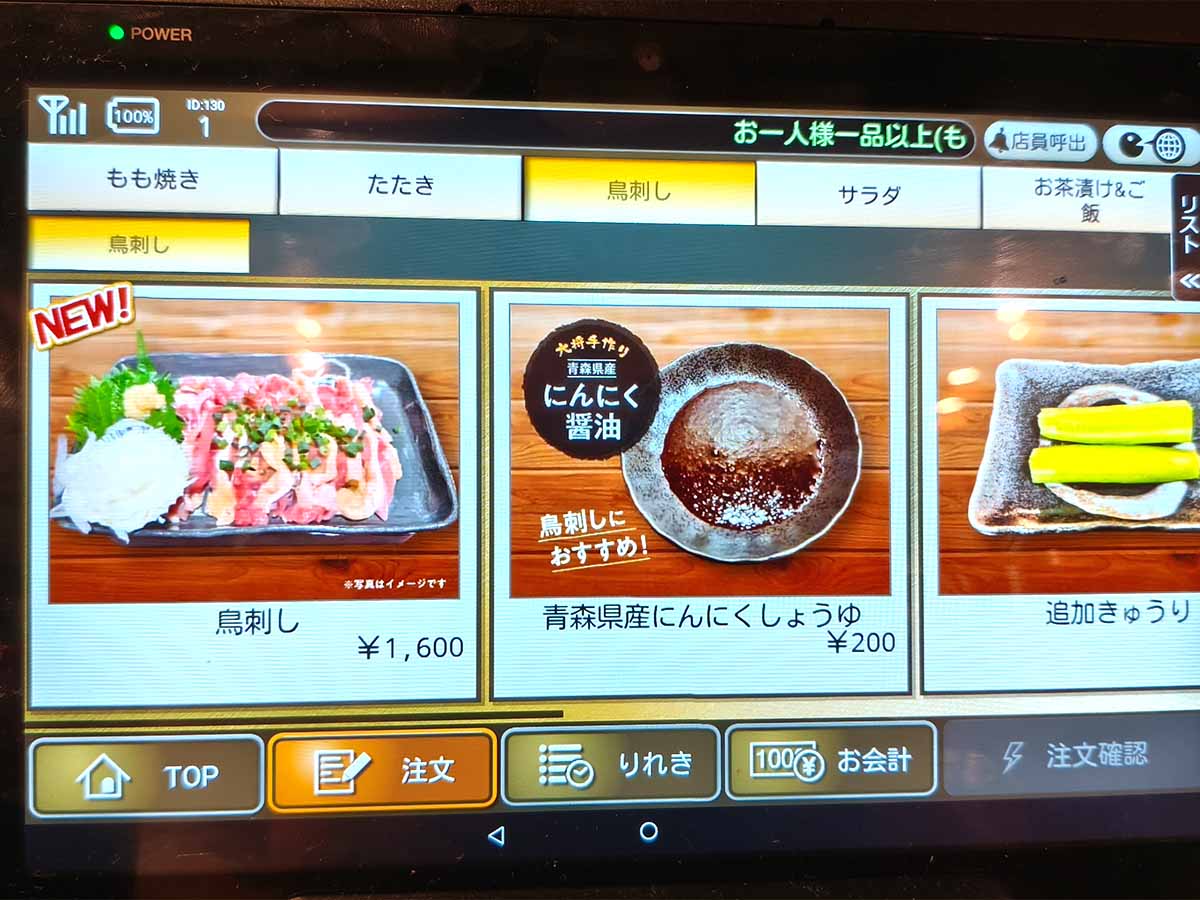 丸万焼鳥 支店のタッチパネルに表示された鳥刺し1600円と、鳥刺しにおすすめの青森県産にんにく醤油