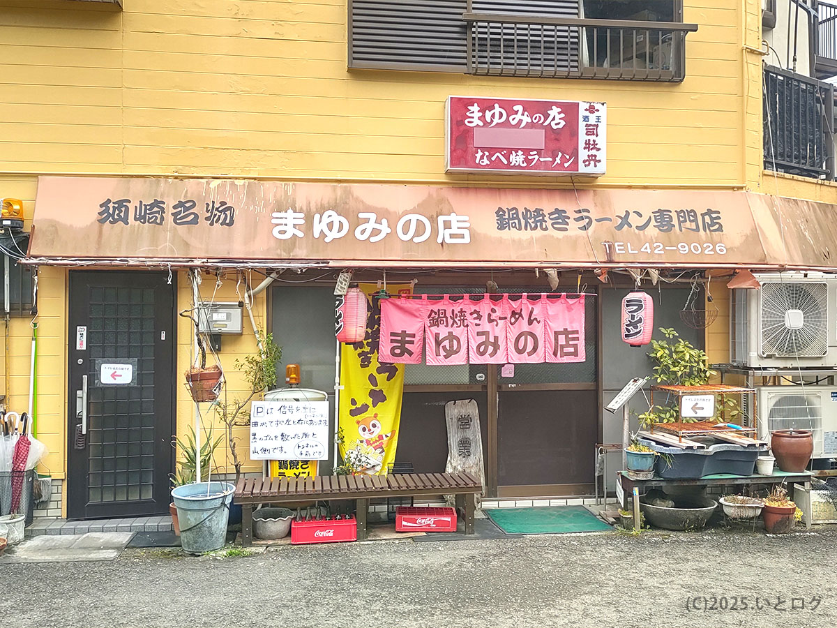 須崎名物と掲げる外観。黄色い壁に茶色いひさしが目印の〈まゆみの店〉鍋焼きラーメン専門店、営業時間案内も。