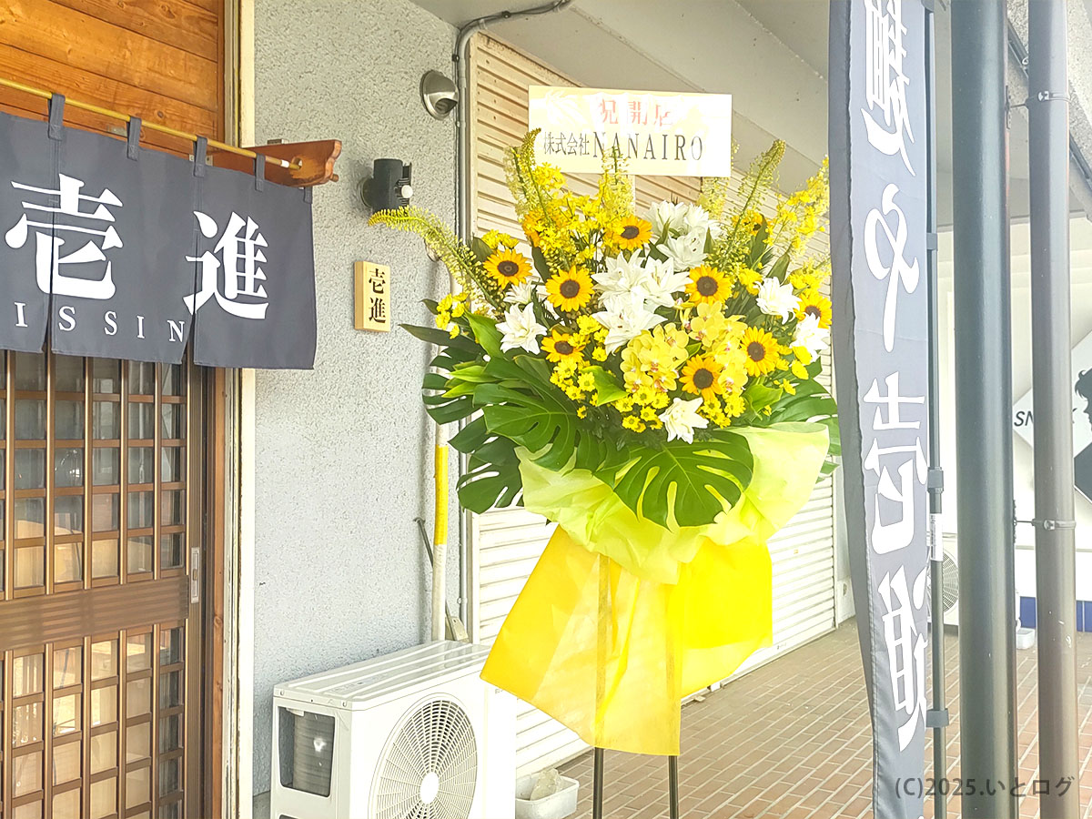ヒマワリと白百合が華やぐ開店祝いのスタンド花—山梨ラーメン新店舗「麺や壱進」玄関を彩り、甲斐市ラーメンシーンに鮮烈デビューを告げる