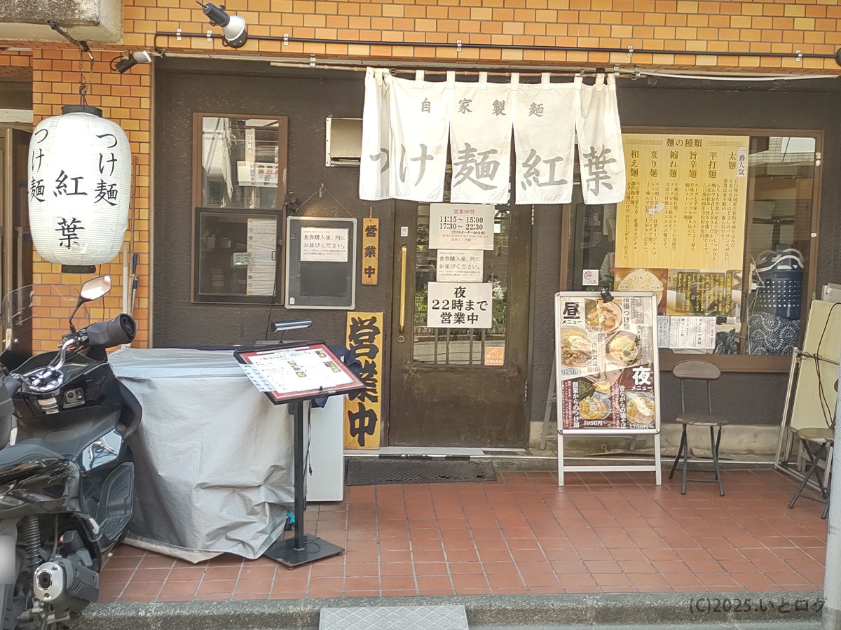 国分寺駅近くの「つけ麺紅葉」外観。白いのれんと提灯が目印の自家製麺専門店。昼夜でメニューが変わるスタイルが特徴のラーメン紅葉。
