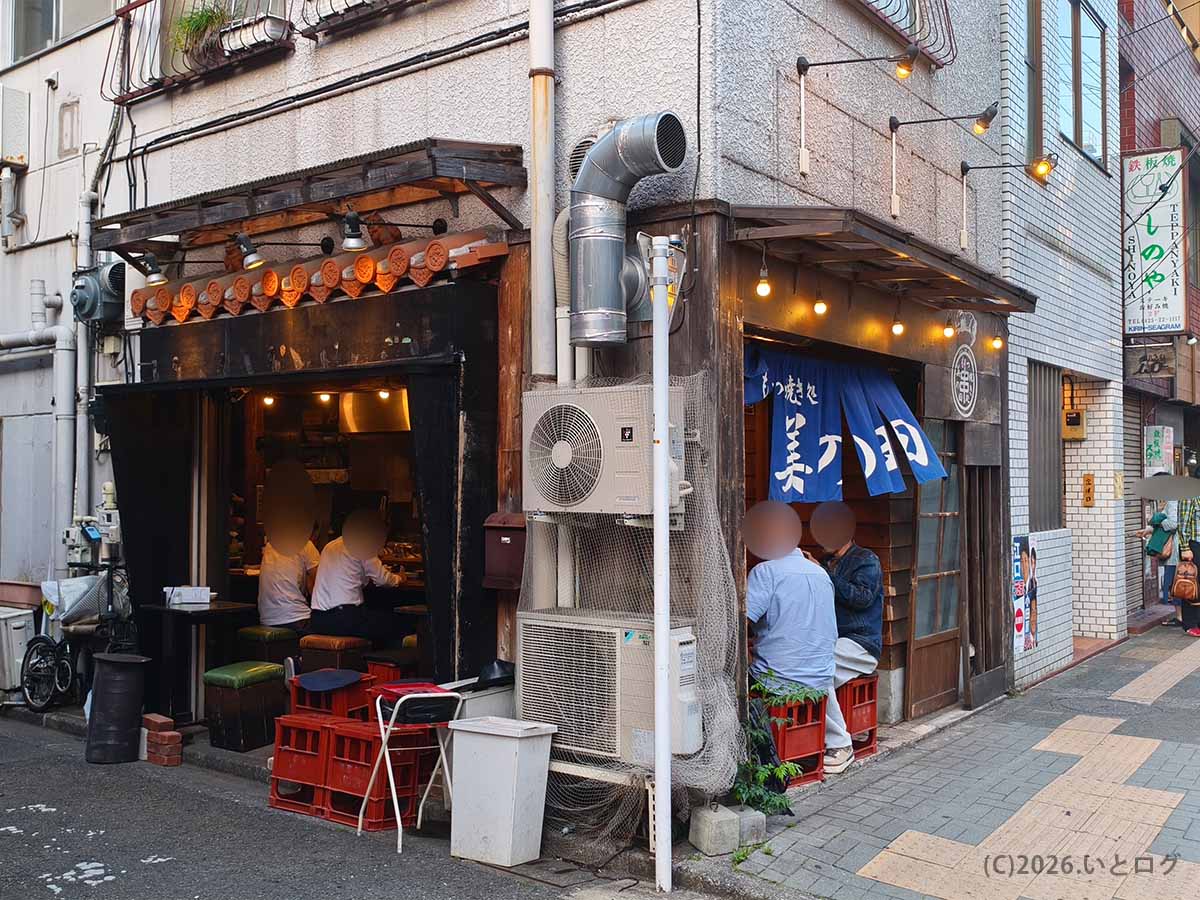 立川駅近くにあるもつ焼き処 美の田の店舗外観と、青い暖簾が掛かった入口