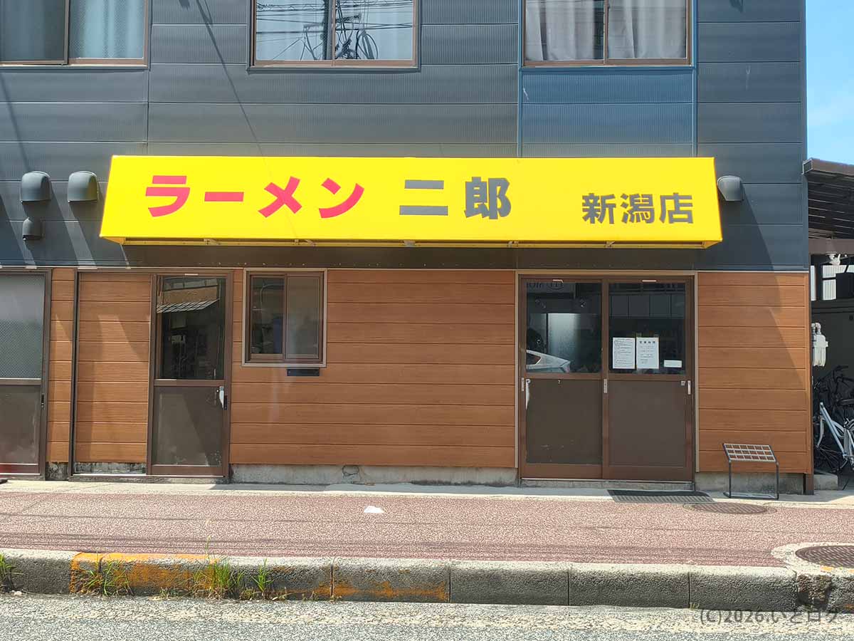 新潟県新潟市中央区万代にあるラーメン二郎 新潟店の外観。黄色い看板に赤と黒の文字で店名が書かれている。