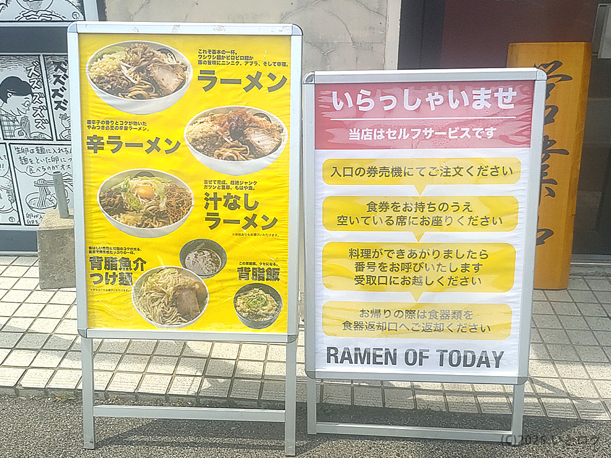 RAMEN OF TODAY 下松店（下松市）の店頭看板。定番のラーメン、辛ラーメン、汁なし、背脂魚介つけ麺などメニューが並ぶ。セルフサービス方式を案内する看板も設置され、ラーメンオブトゥデイらしいポップなデザイン。