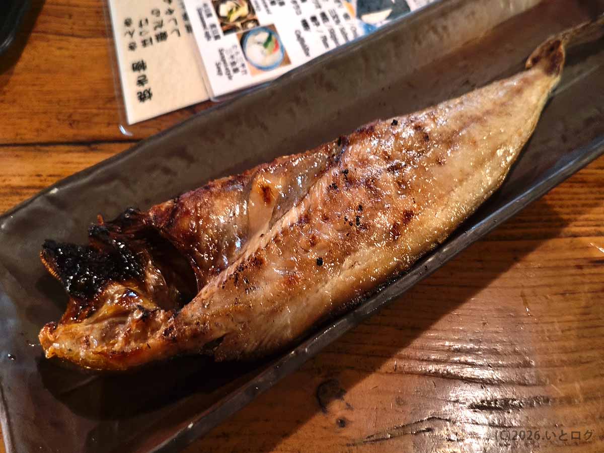 炉端焼き発祥の店「炉ばた」で提供された焼き魚。細長い黒い皿に、皮にこんがりと焼き色がついた魚が一尾盛られている