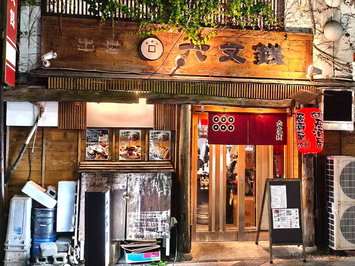 静岡県浜松市にある居酒屋「六文銭」の店舗外観。木造の看板と赤い暖簾が目印