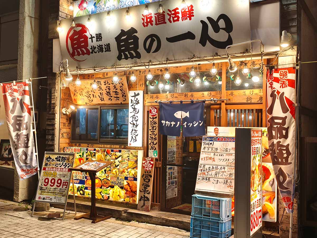 帯広駅から徒歩約5分の海鮮居酒屋「浜直活鮮 魚の一心」の夜の外観。大きな店名看板と刺身8品盛り888円の案内が目立つ店舗入口。