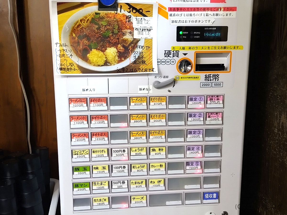 鷹の目 西巣鴨店の券売機。ラーメン・まぜそばの基本メニューから限定ボタン、トッピング追加まで一目でわかる構成。訪問時はラストオーダー前でも行列必至。