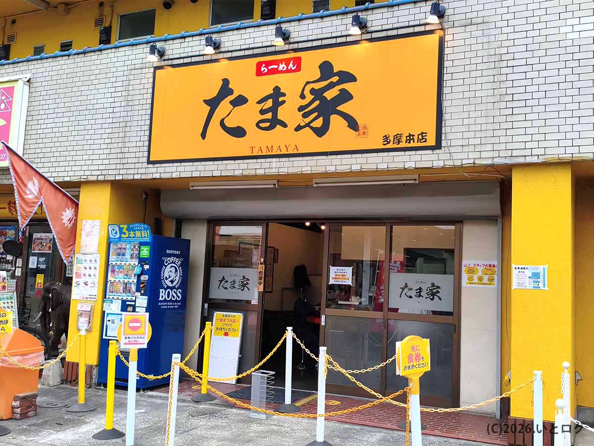 東京都多摩市にある家系ラーメン店「らーめん たま家 多摩本店」の黄色い看板と店舗入口