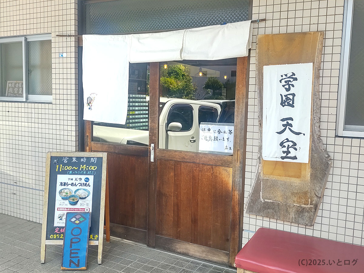 松江市学園エリアにある学園天空の外観。木の看板に力強い筆文字で『学園天空』と掲げられ、営業時間の案内板も設置。松江天空おすすめのラーメンを求めて訪れる人が多く、駐車場も完備している。