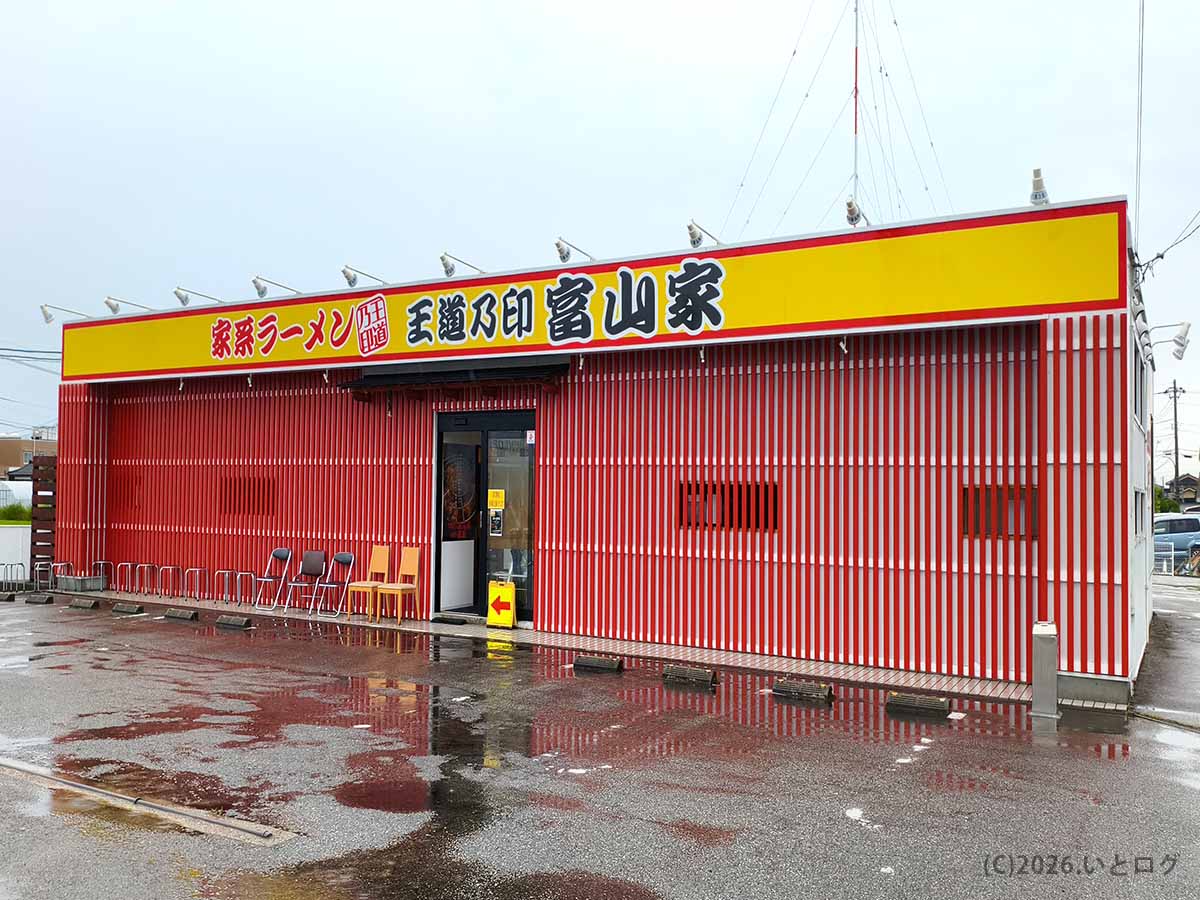 富山市新屋にある家系ラーメン店「王道乃印 富山家」の外観。赤と白の建物に黄色い看板が目立つ、王道家系ラーメンの新店。