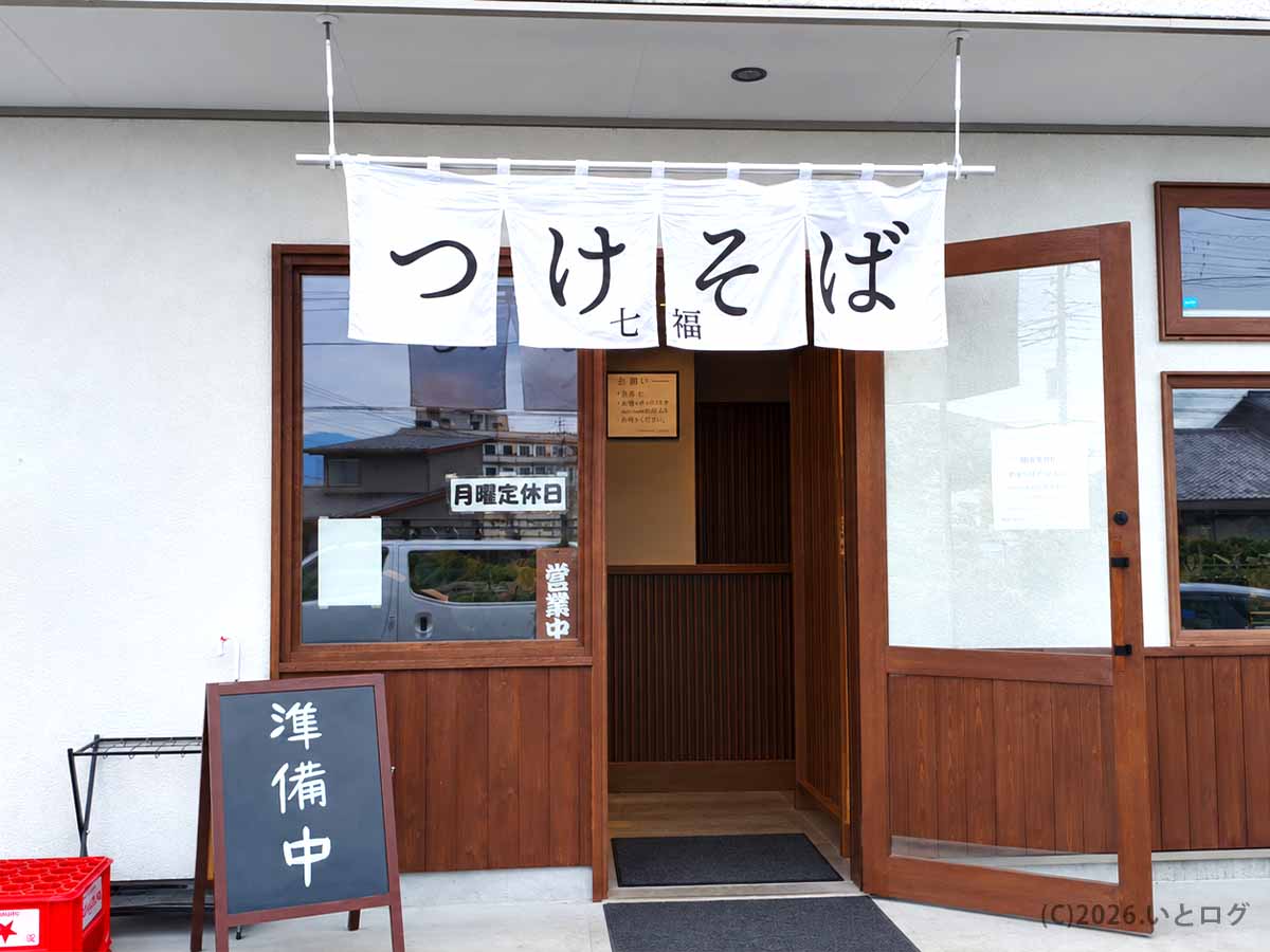 白い暖簾に「つけそば 七福」と書かれた山梨県甲府市上今井の店舗外観